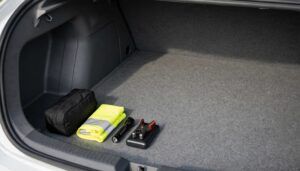 A small emergency kit and a few essentials sit in one corner of a mostly empty sedan trunk.